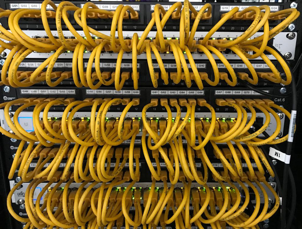 Image of UniFi Switches in Communications cabinet patched with 25cm Yellow cables.