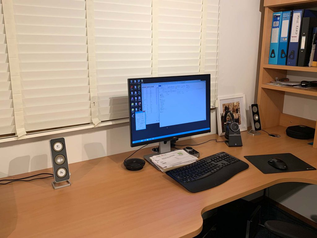 Image of a desk with a monitor, keyboard, mouse etc. Shows the difference in cables when switching to a wireless headset, in this case the Jabra Evolve 75.